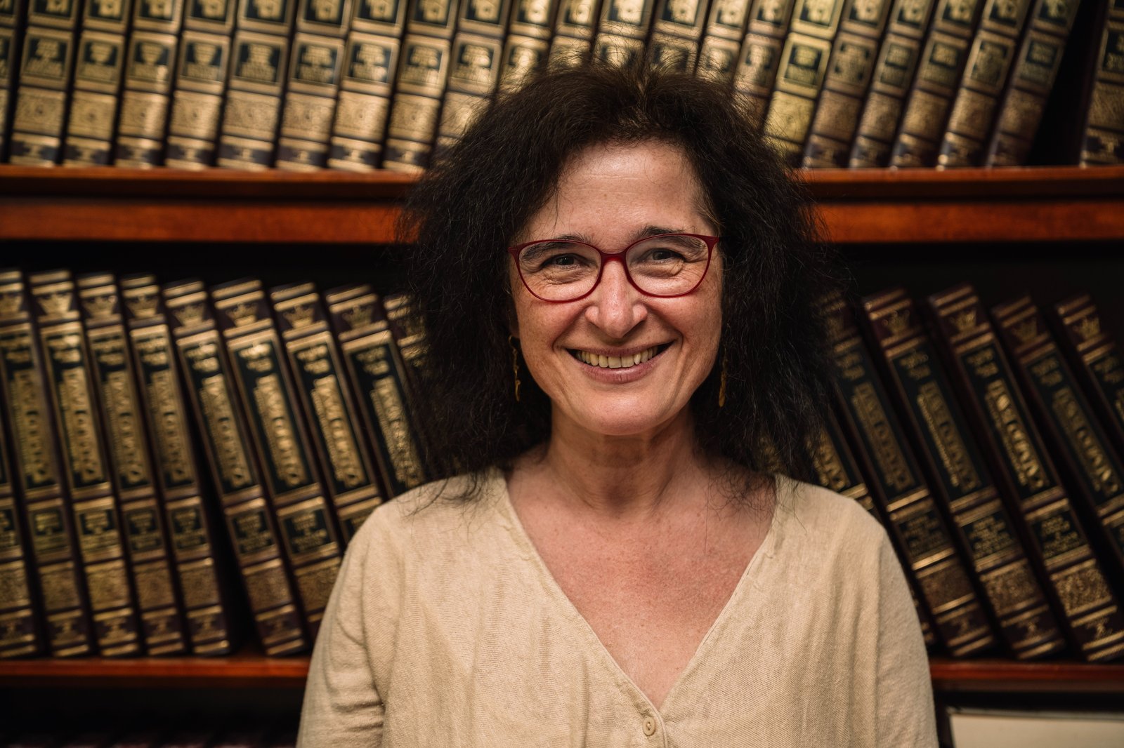 Ágnes Vető, in front of the bound volumes of the Encyclopaedia Judaica.